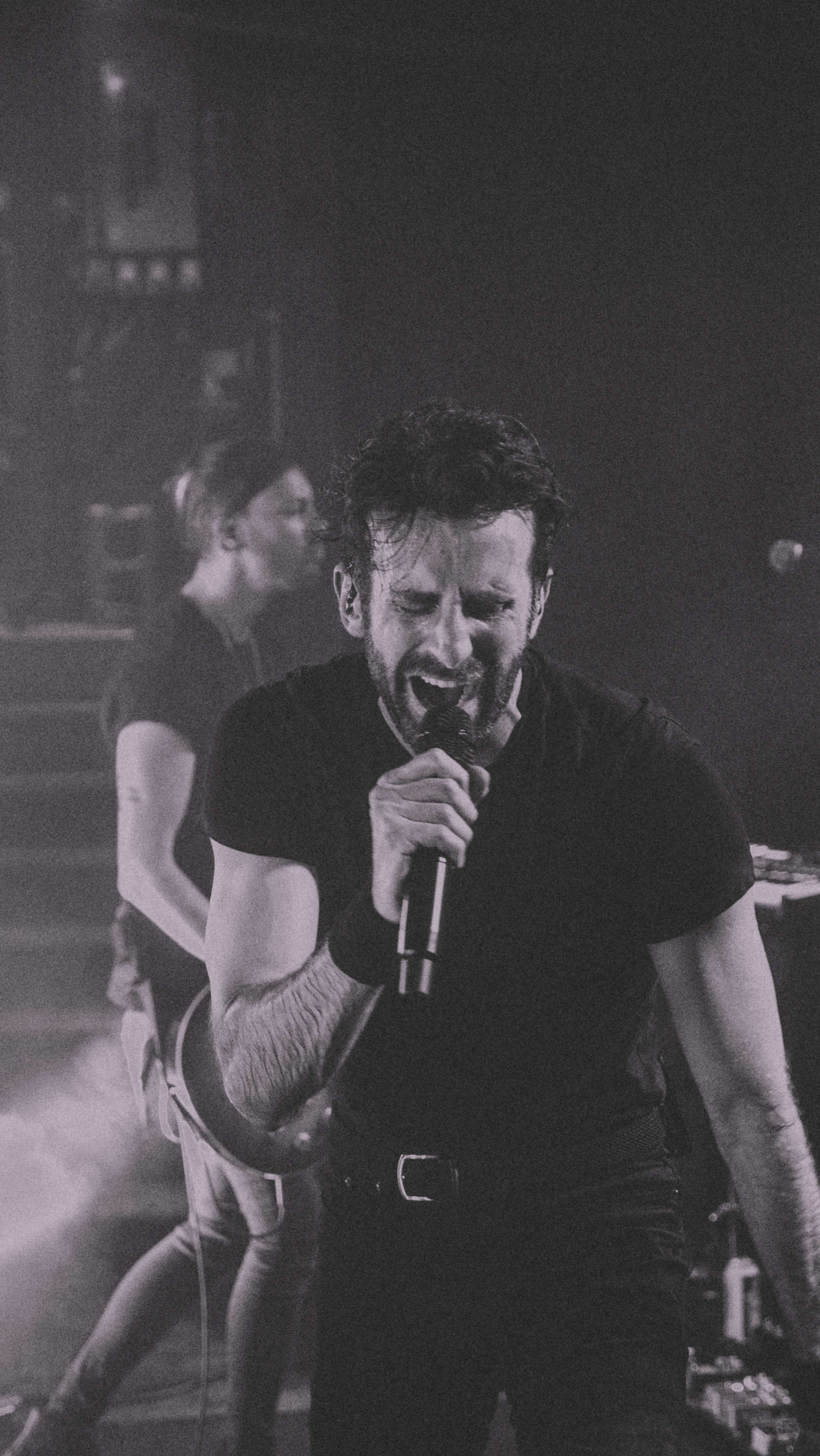a black and white photo of a man singing into a microphone
