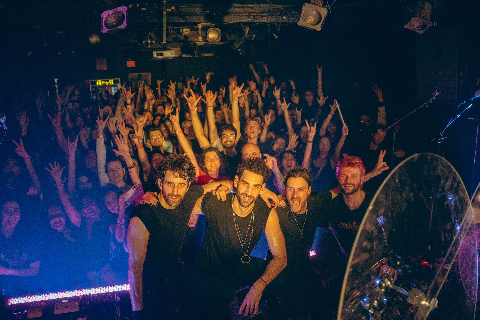 a group of people at a concert with their hands up