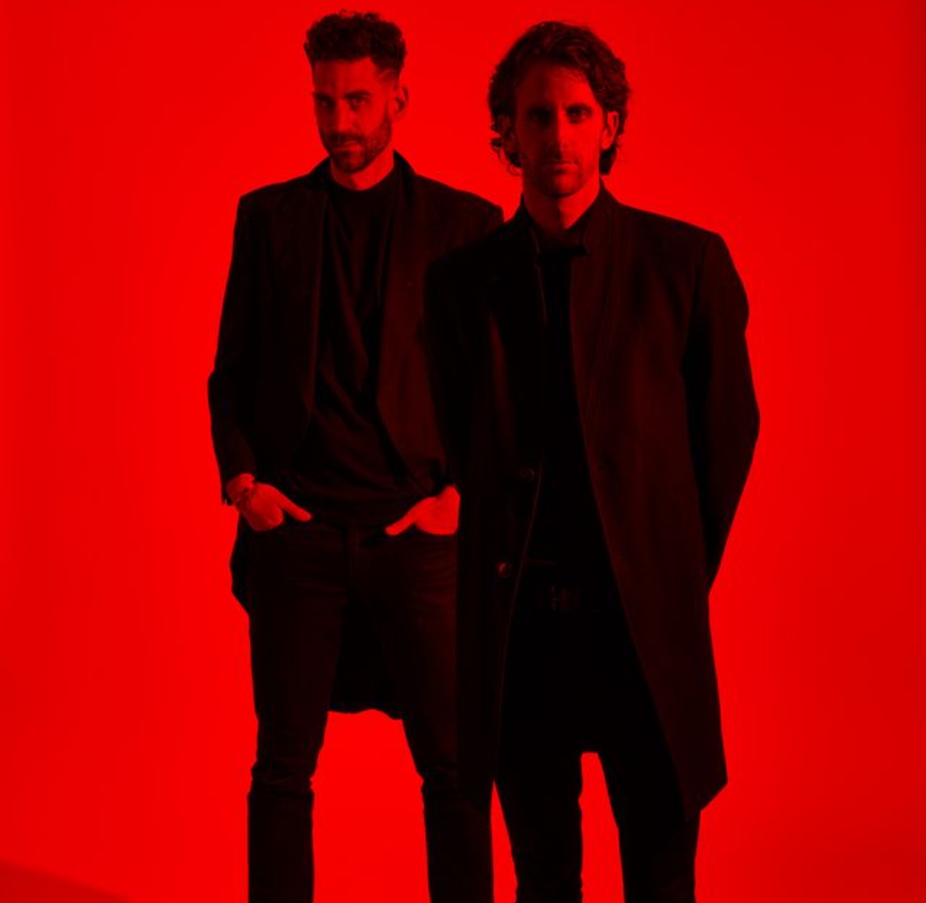 two men standing in front of a red background