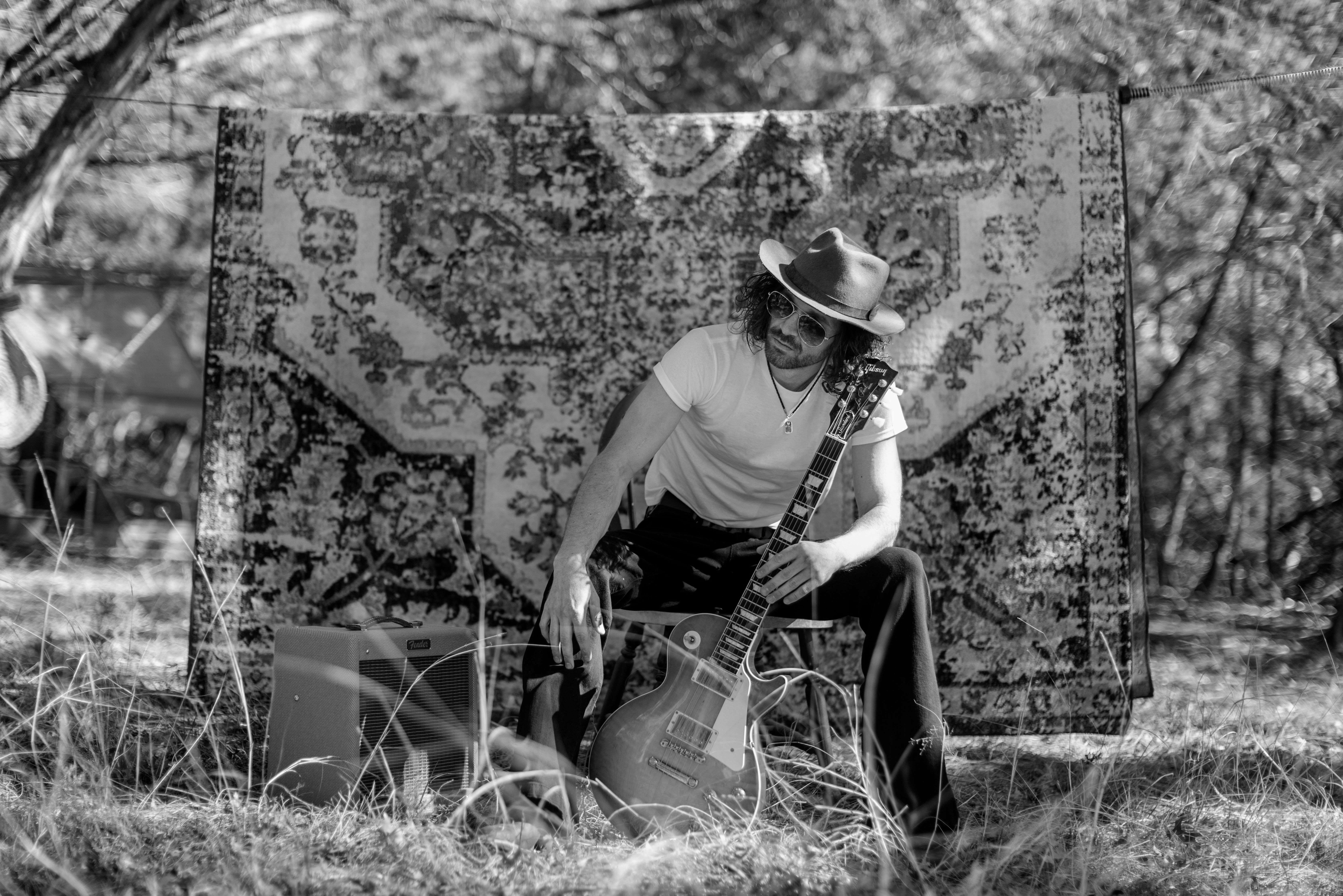 a man in a cowboy hat sitting on a blanket