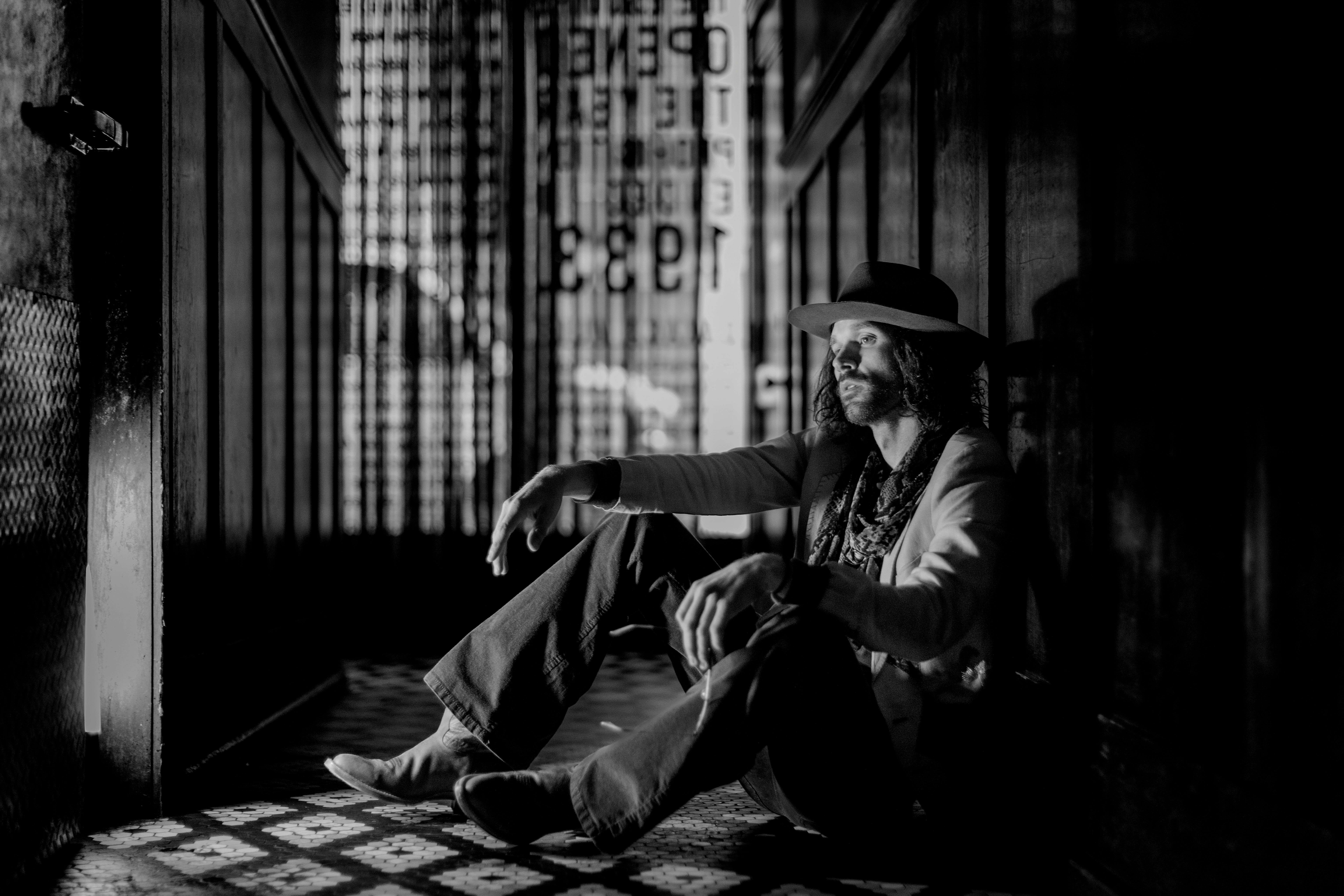 a man in a hat sitting on a tiled floor