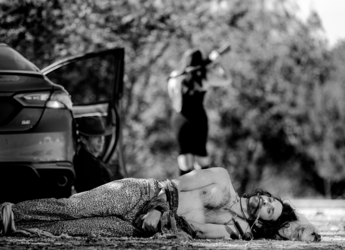a man laying on the ground next to a car