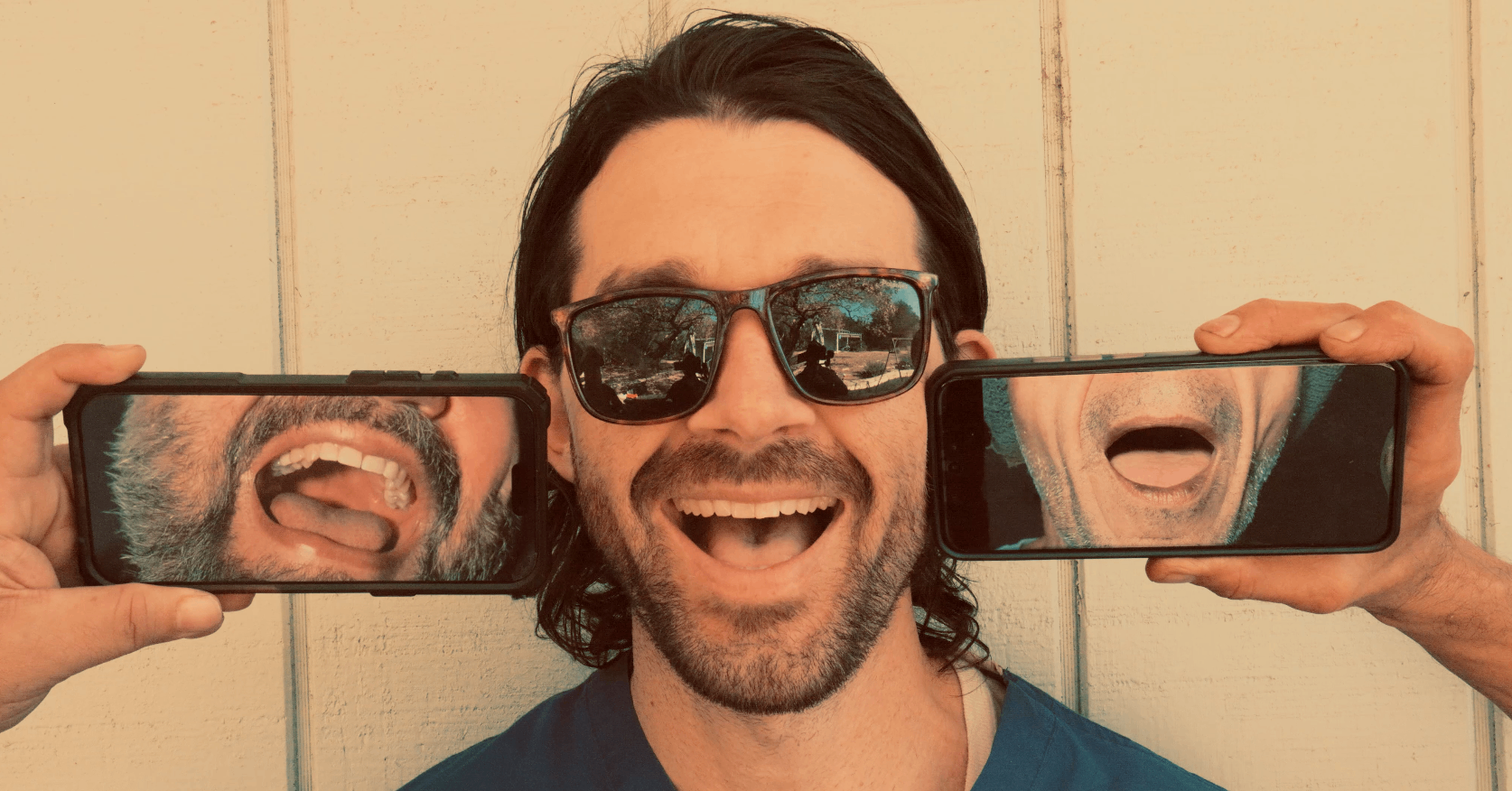 a man is holding up two smartphones with his mouth open