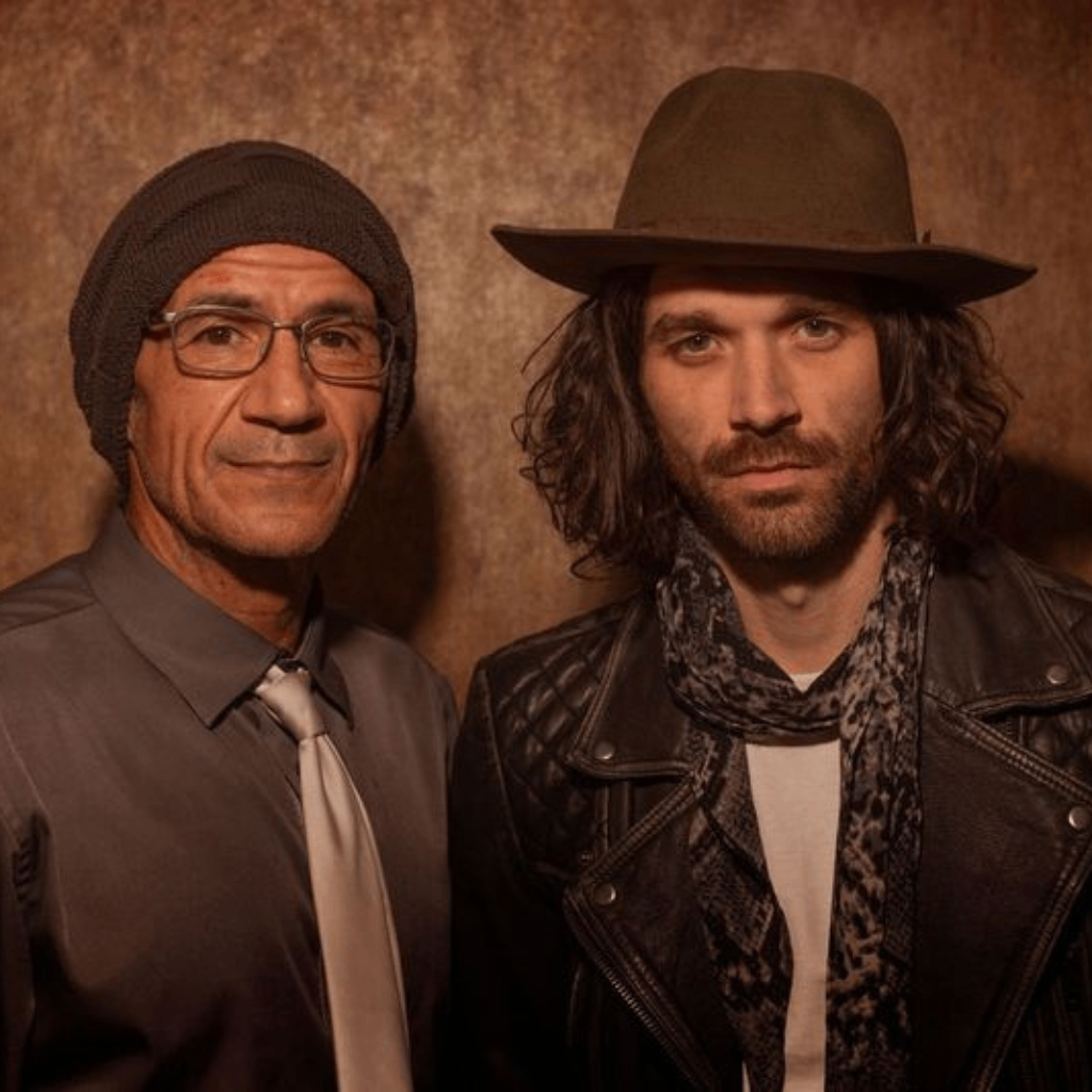 two men standing next to each other wearing hats and jackets