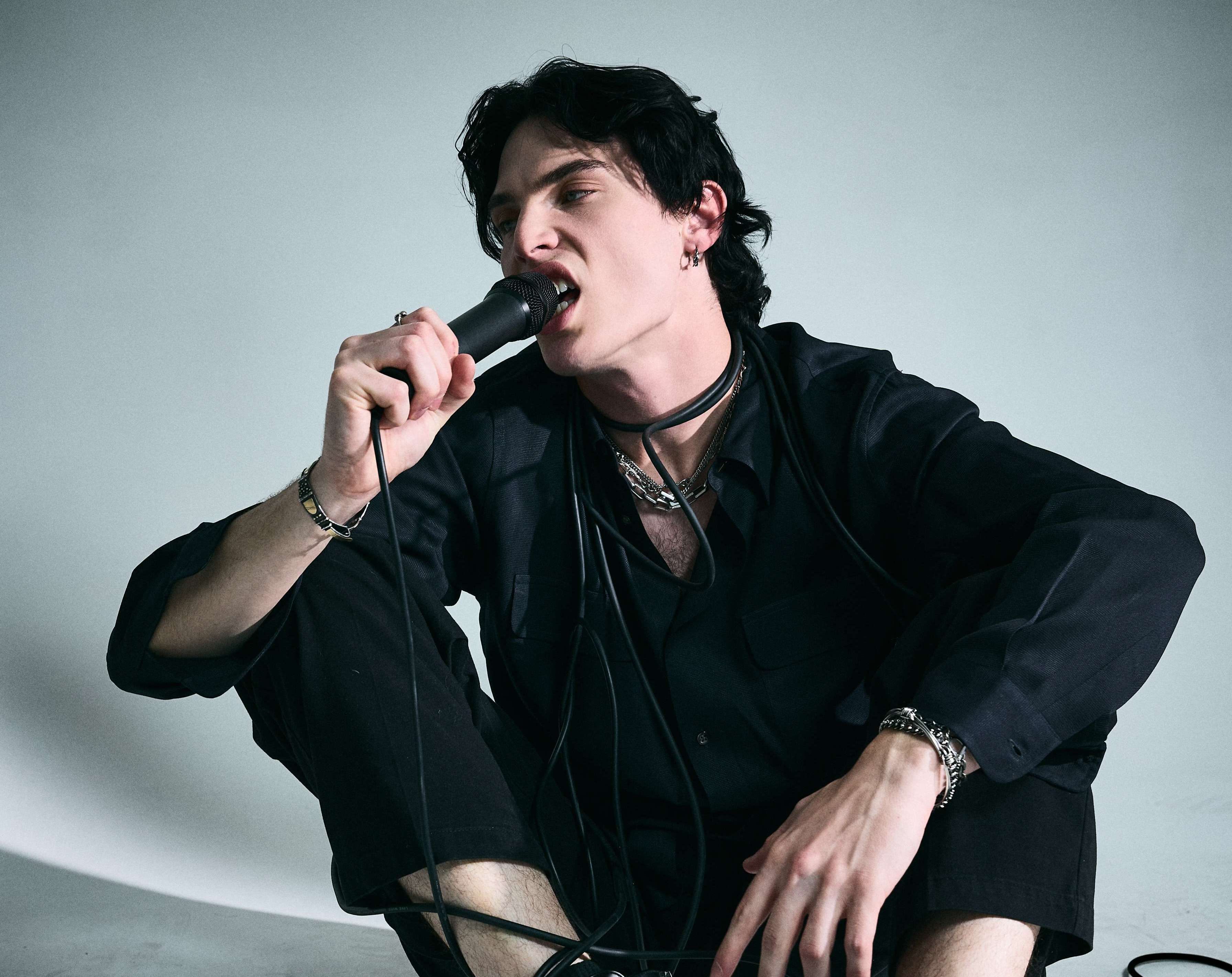 a man is sitting on the ground and holding a microphone