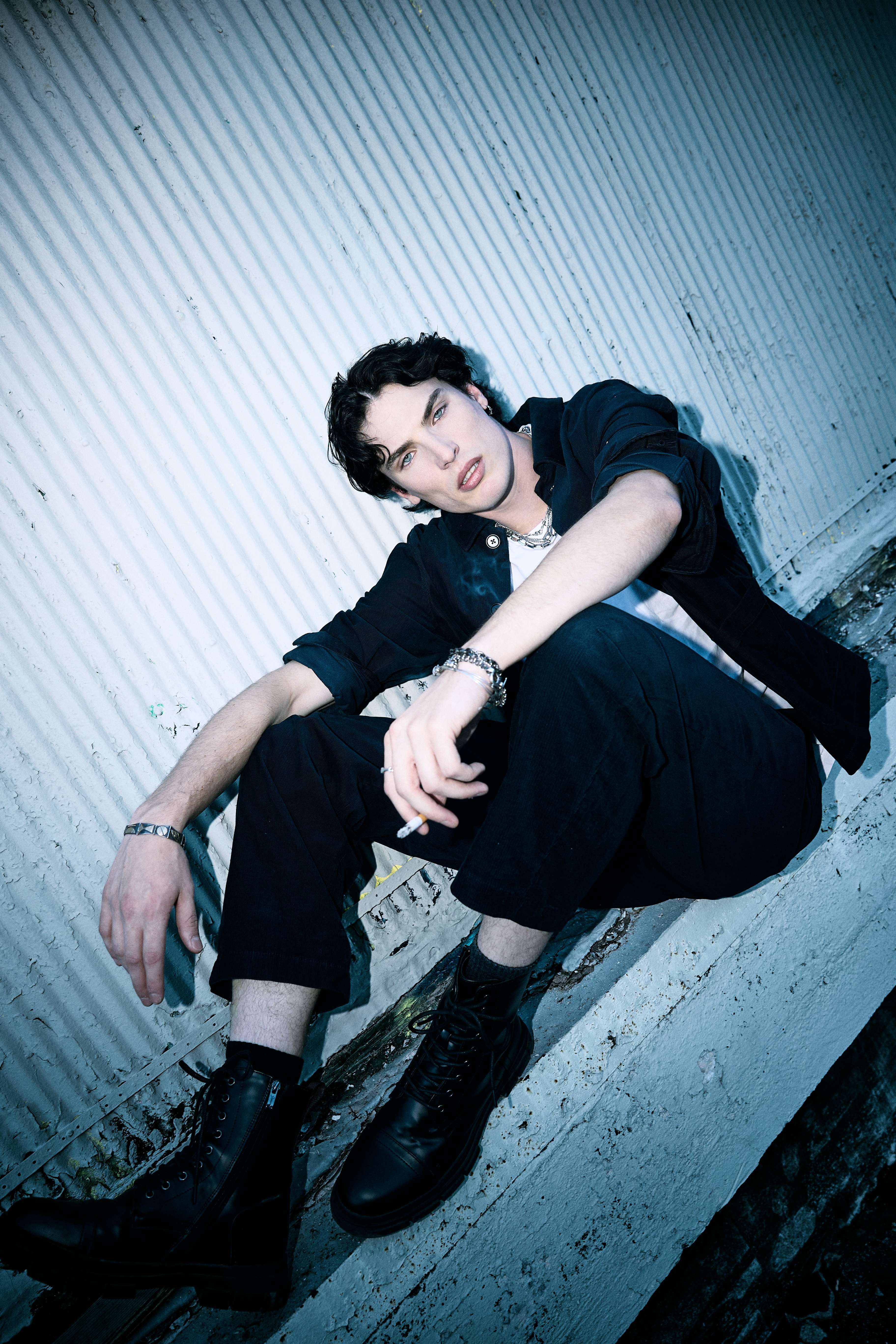 a young man sitting on the edge of a building