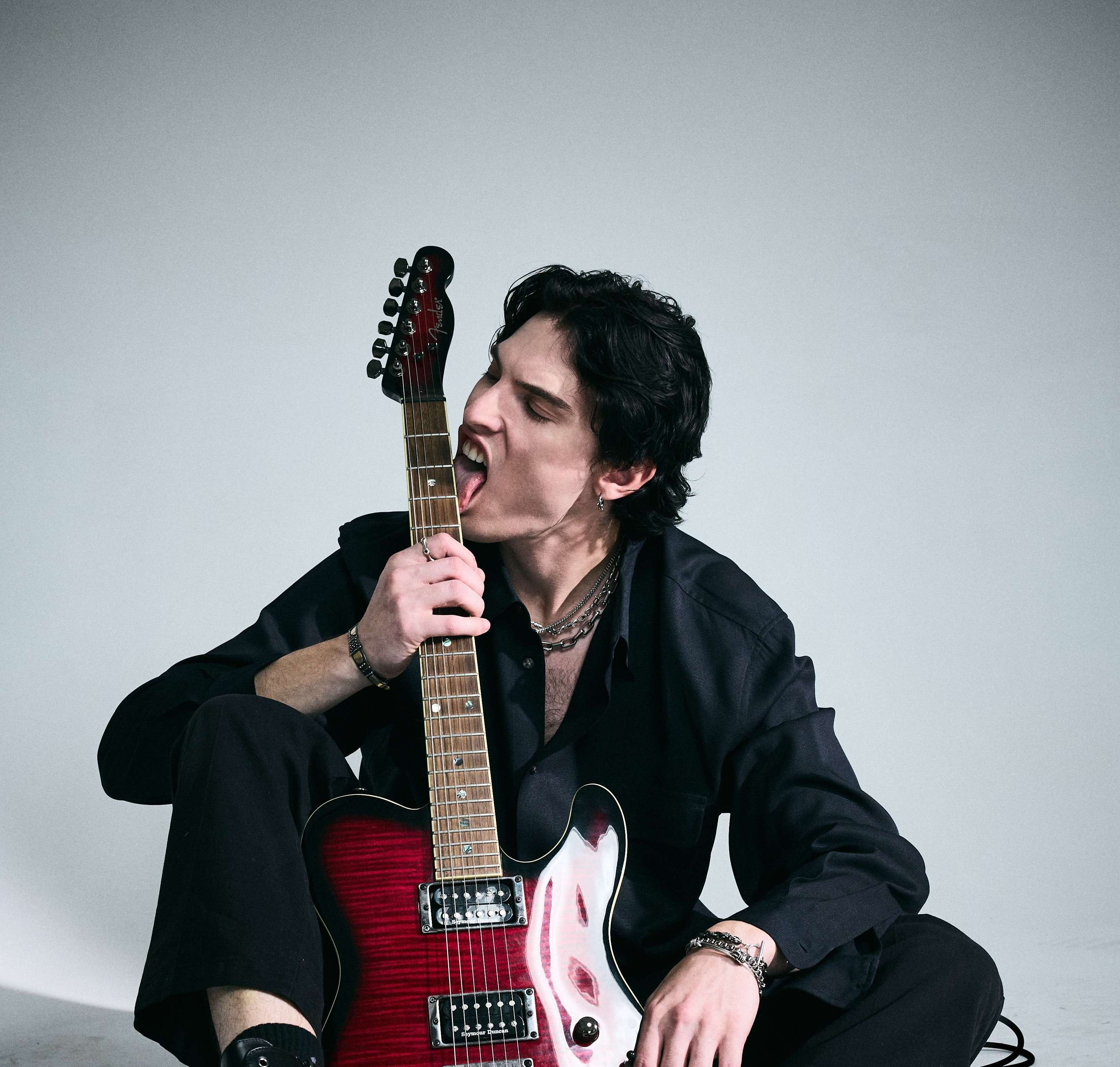 a man sitting on the floor with a red electric guitar