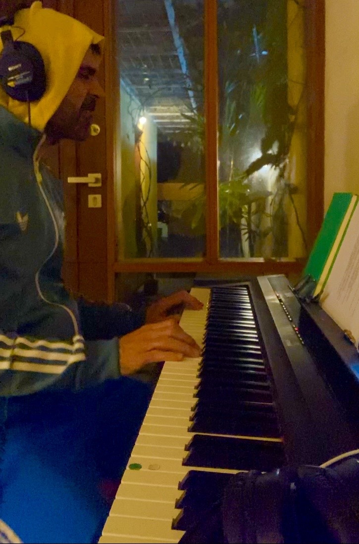 a man with headphones playing a piano in a room