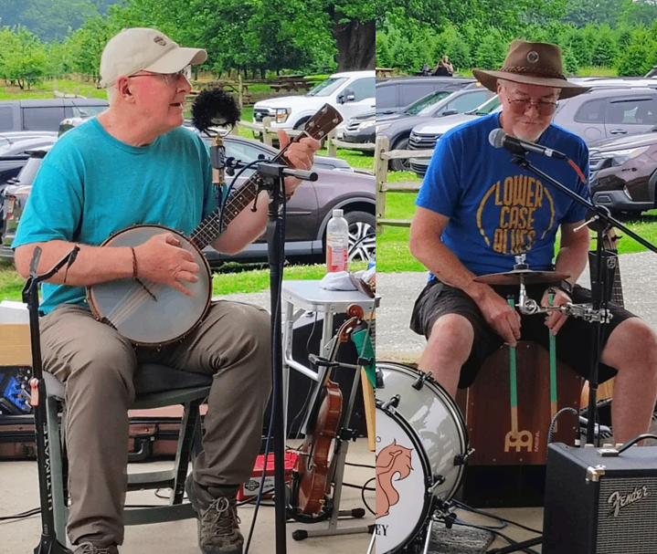 two men playing banjo and guitar at an outdoor event
