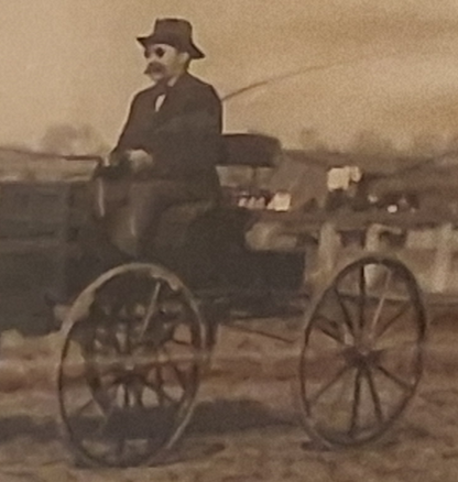 an old photo of a man driving a horse drawn carriage