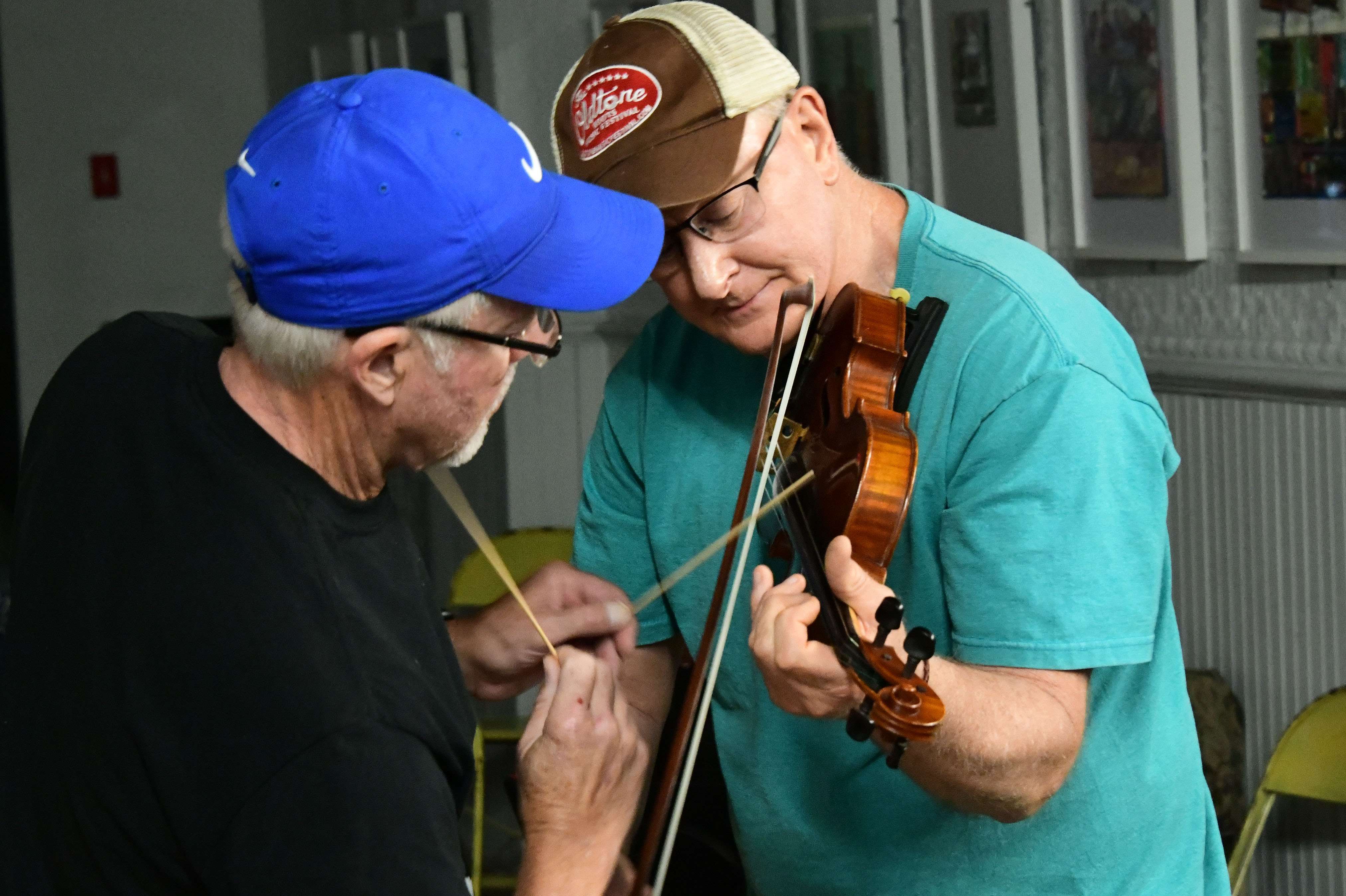 two men playing a violin in a room