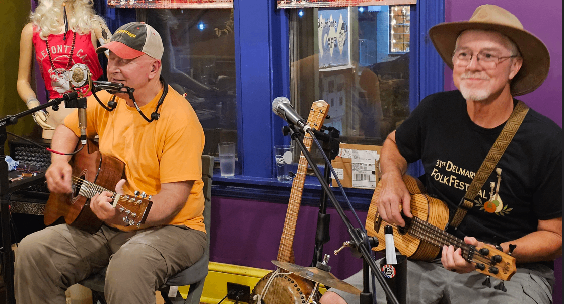 two men in hats playing guitars in a room