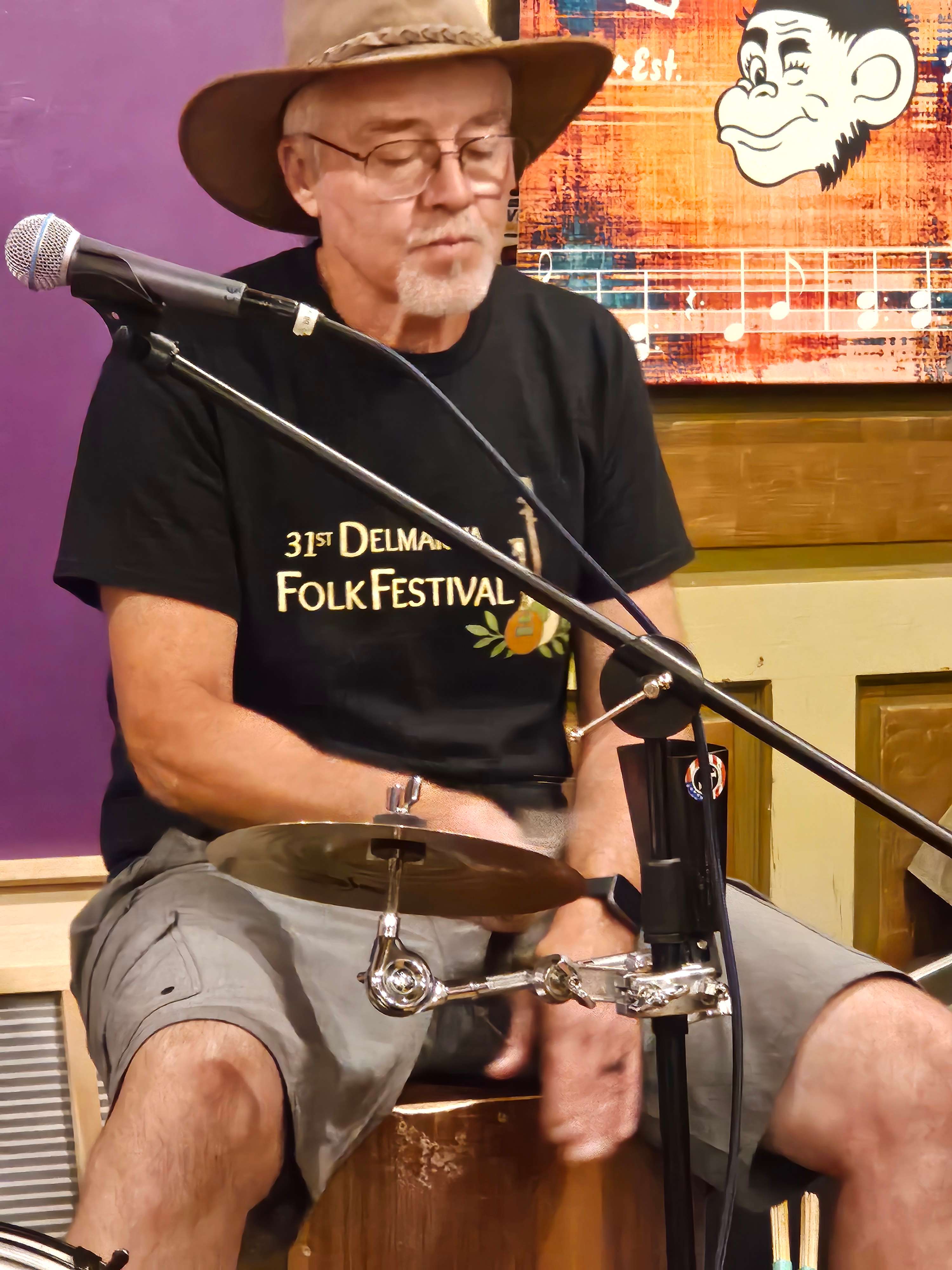 a man in a hat sitting at a microphone