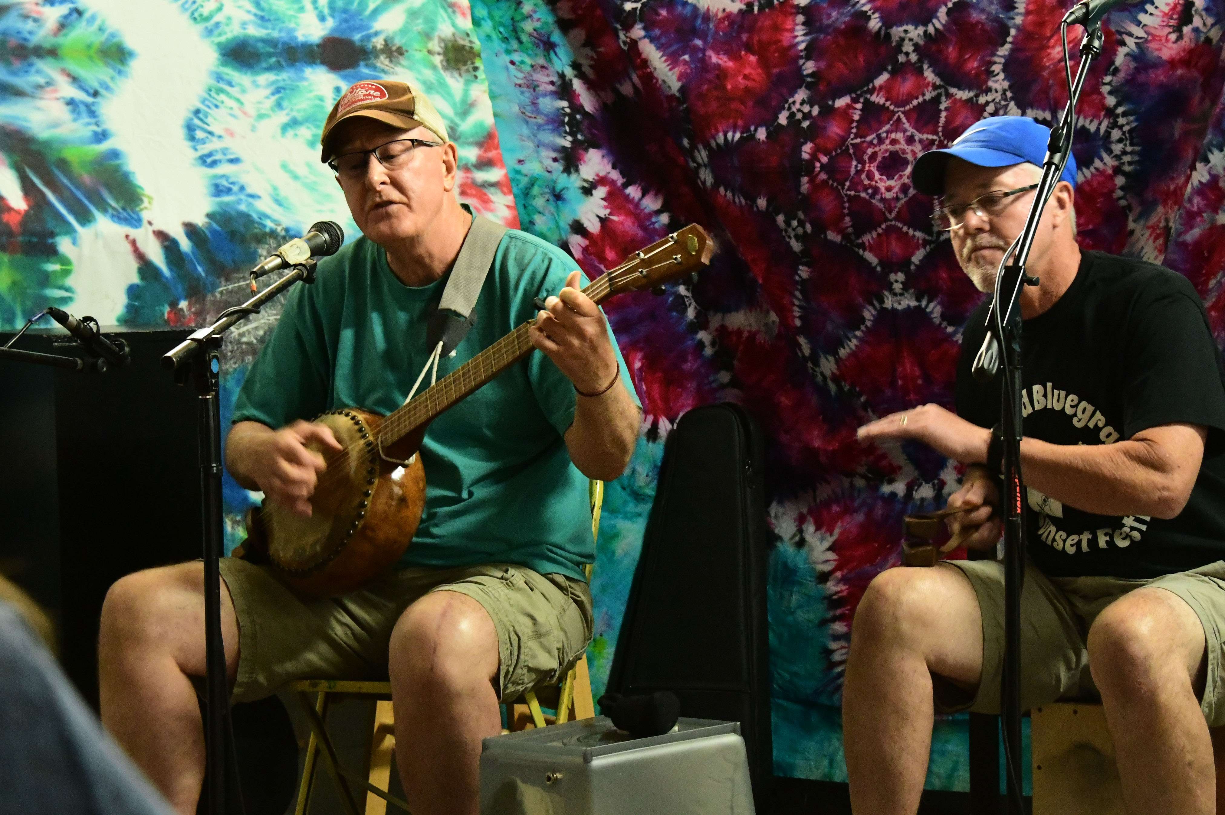 two men playing guitars in front of a mural