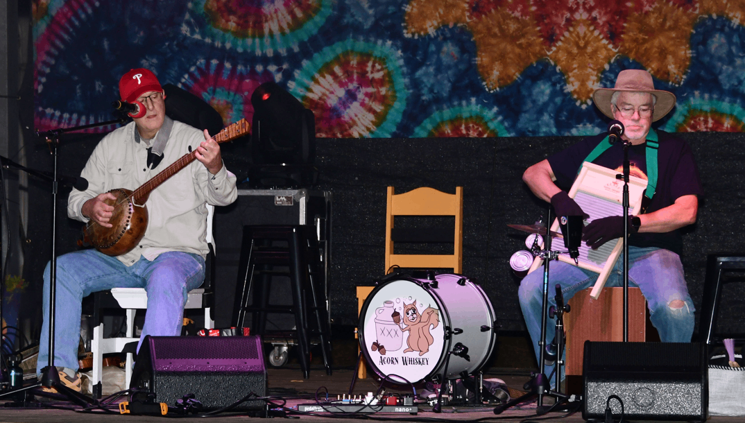 two men playing music on stage at a festival