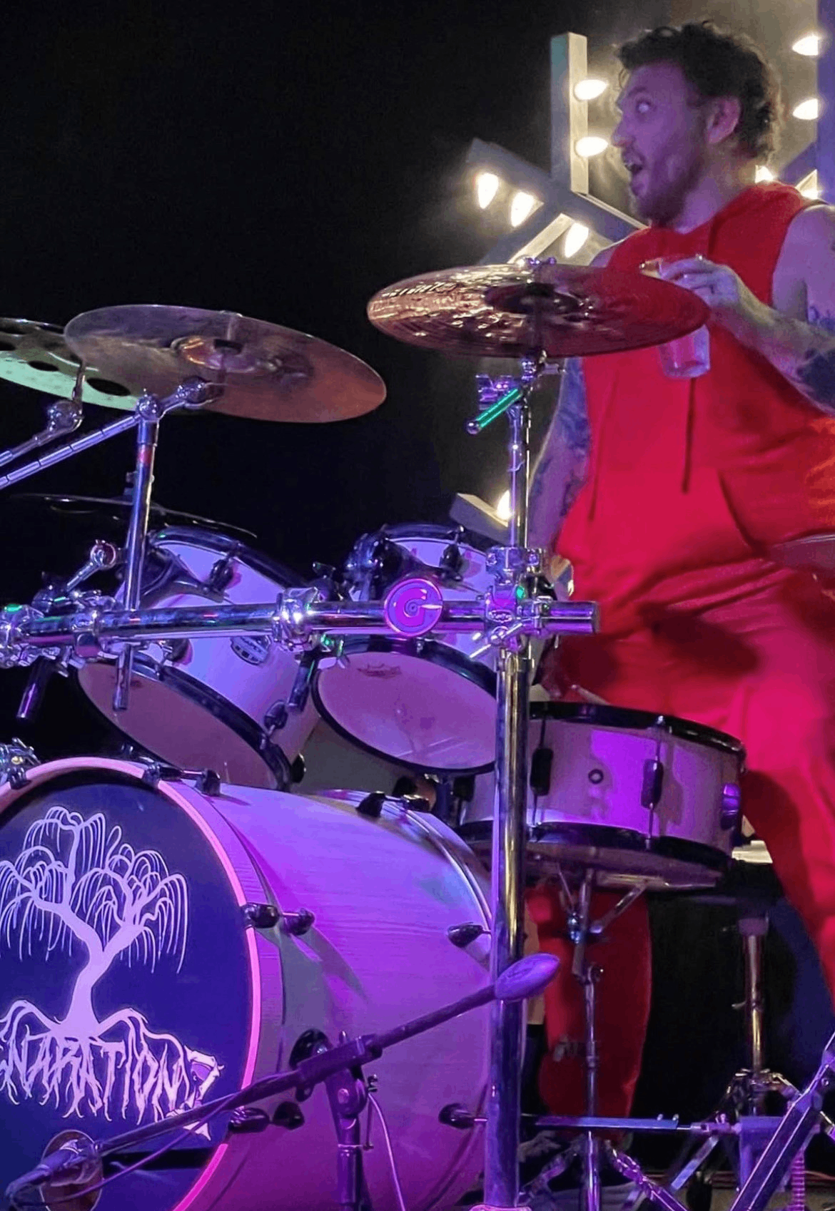 a man in red playing drums on stage