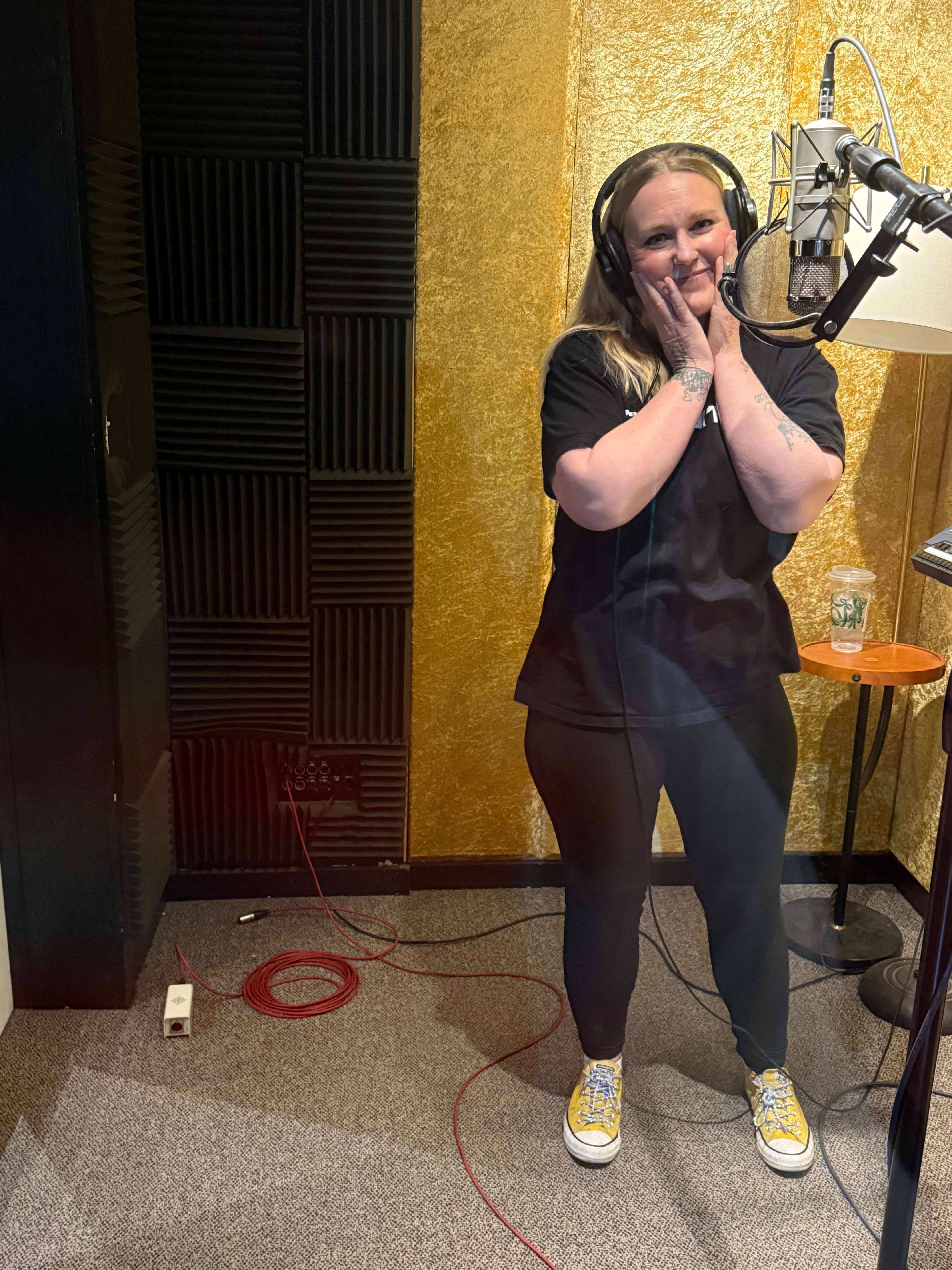 a woman standing in front of a microphone in a recording studio