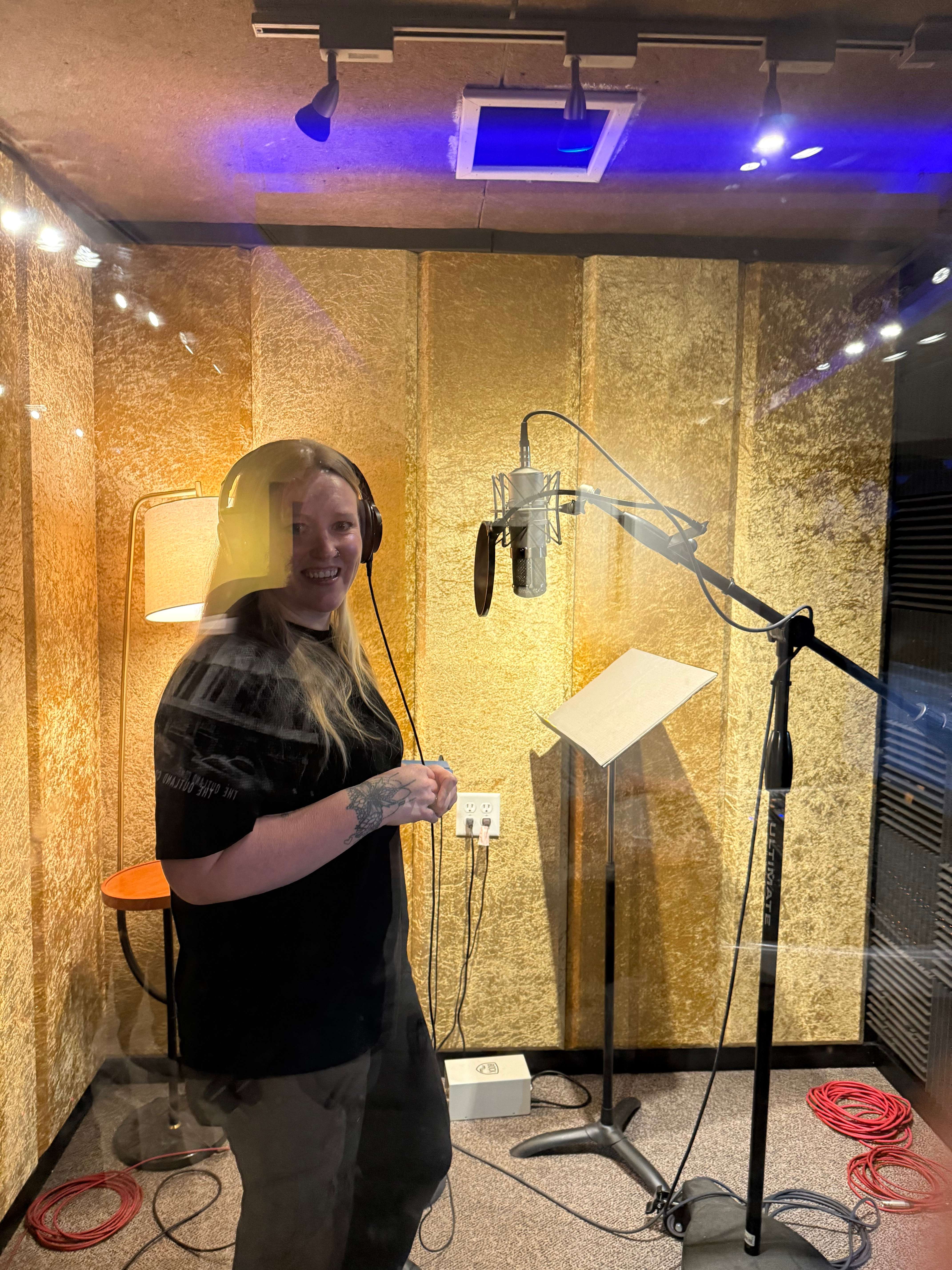 a woman standing in front of a microphone in a recording studio